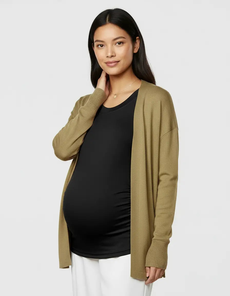 Maternity model in black thermal long sleeve top with side ruching, layered under an olive green cardigan.