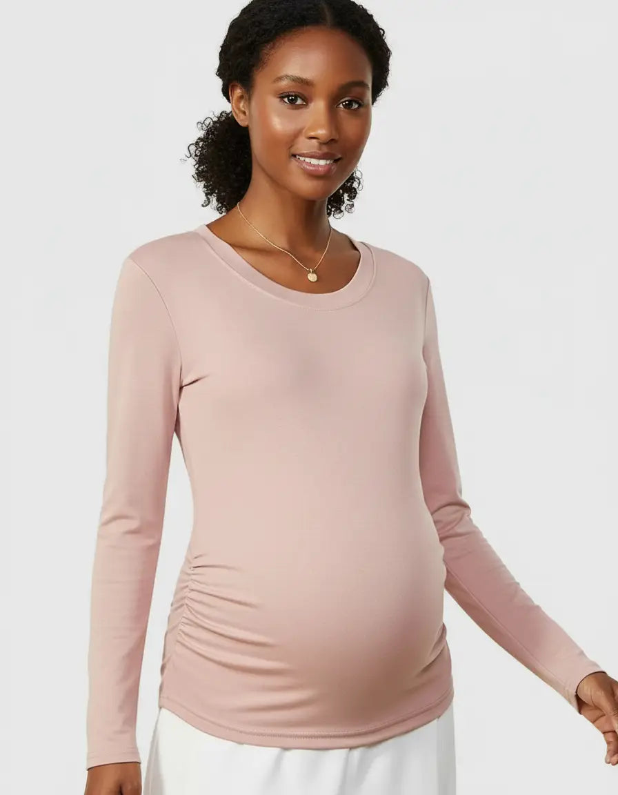 Smiling pregnant woman wearing a soft pink thermal long-sleeve maternity top with side ruching.