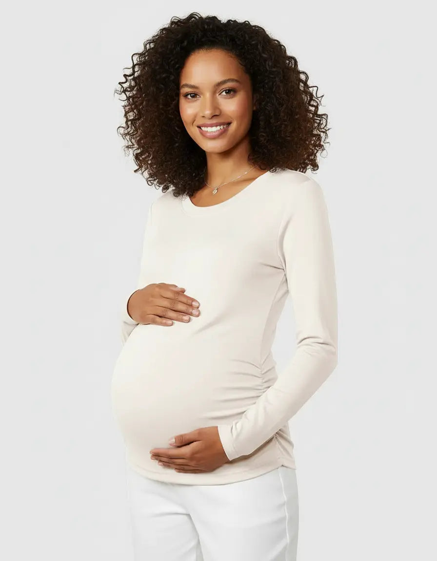 Smiling pregnant woman in a cream thermal long-sleeve maternity top with side ruching.