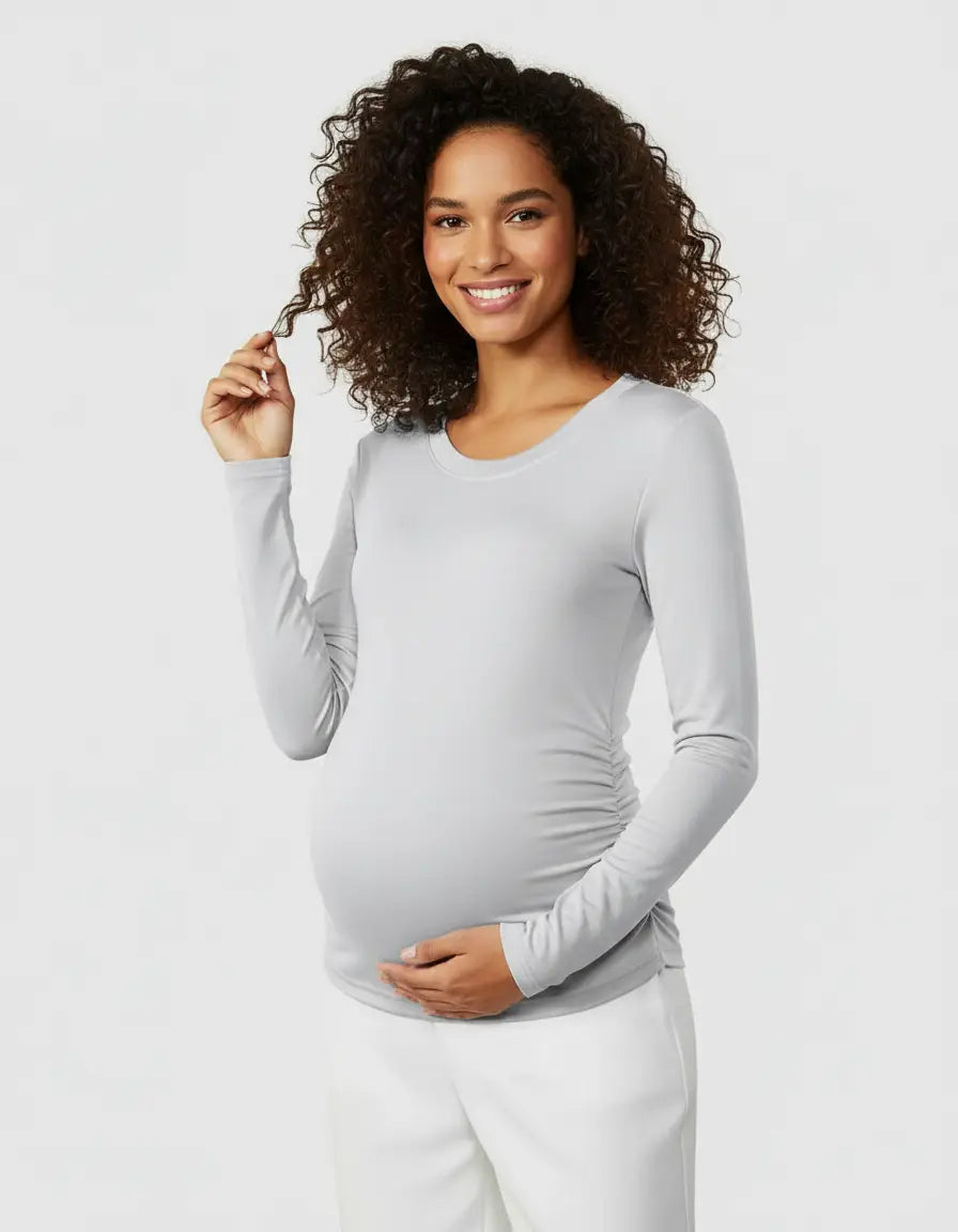 Smiling pregnant woman in a light gray thermal long-sleeve maternity top with side ruching.