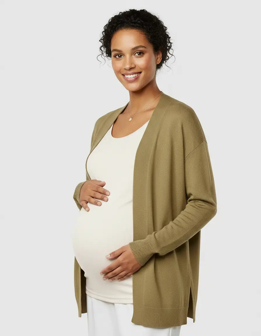 Smiling pregnant woman in a white thermal long sleeve maternity top and olive green cardigan.