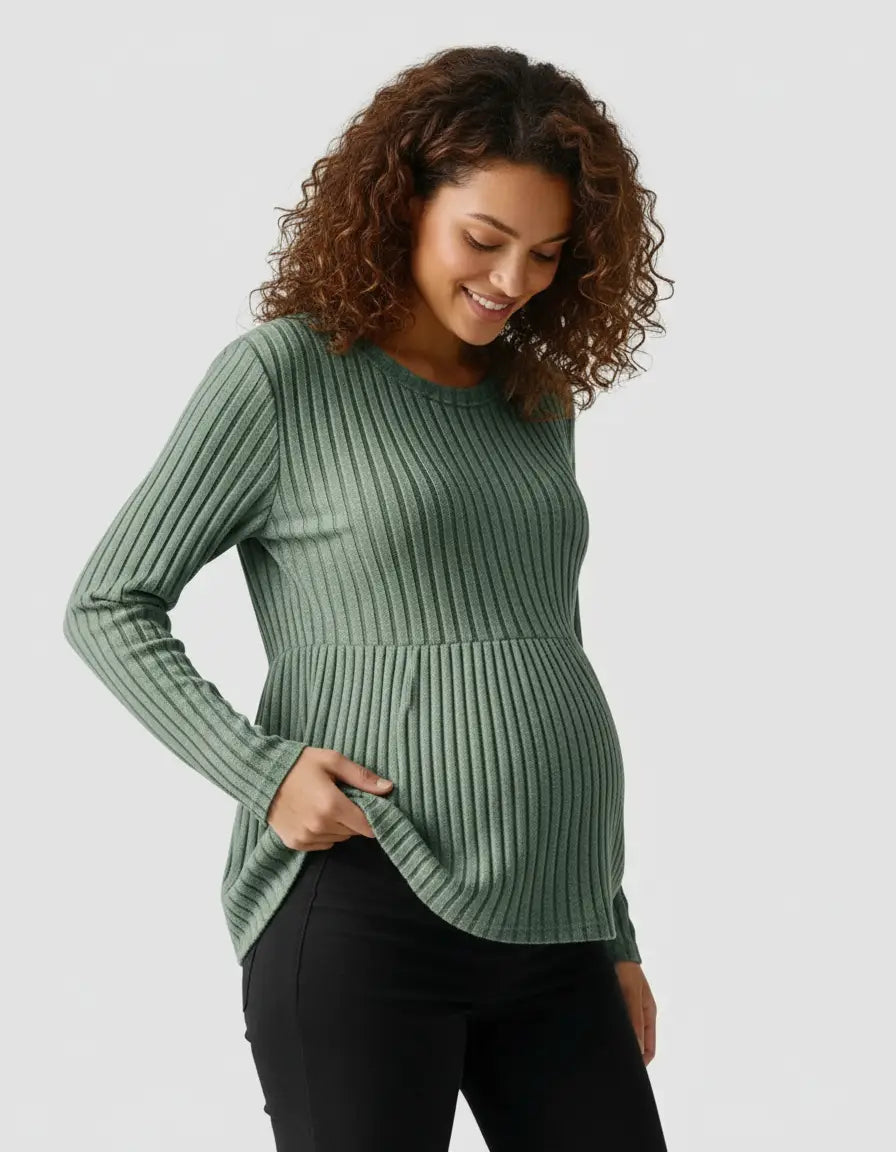 Smiling pregnant woman in a sage green stretch-ribbed maternity top with a peplum hem.