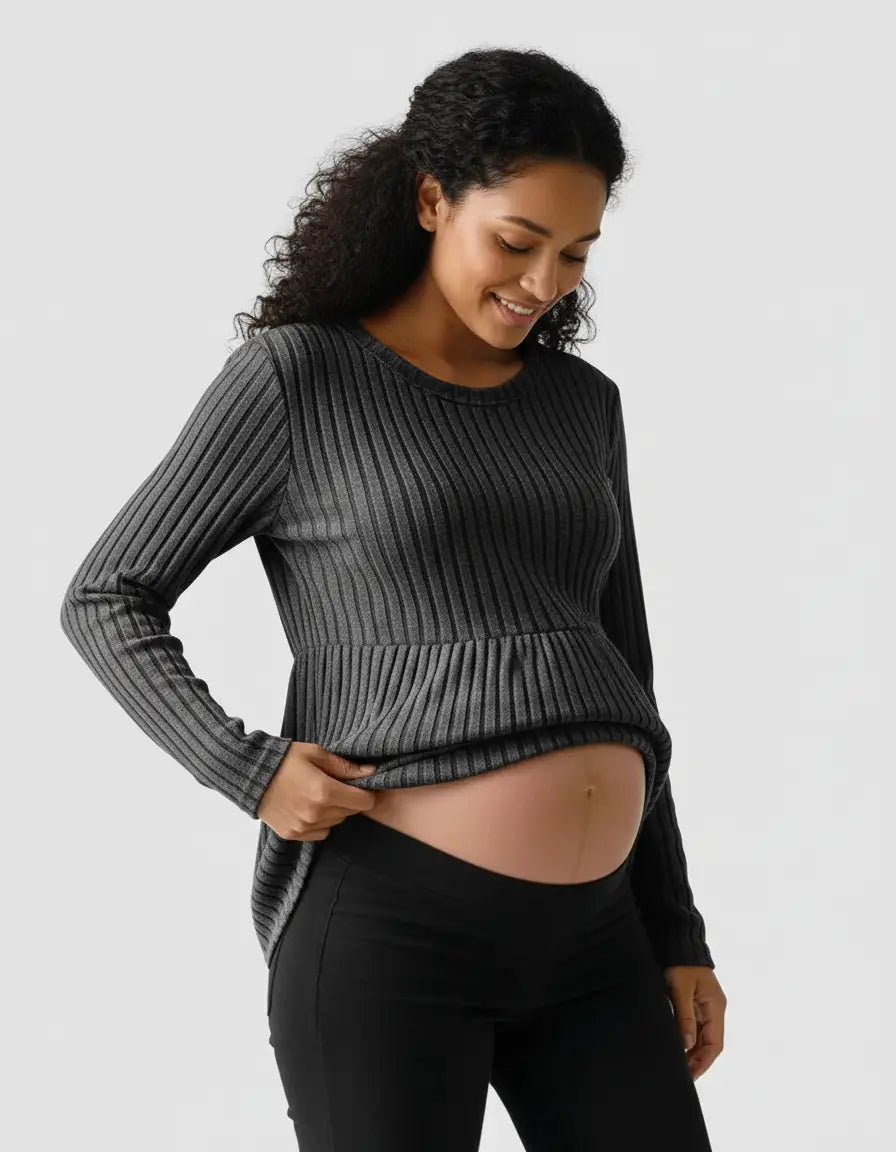 Smiling pregnant woman in a charcoal gray stretch-ribbed casual-fit maternity top with a peplum hem.