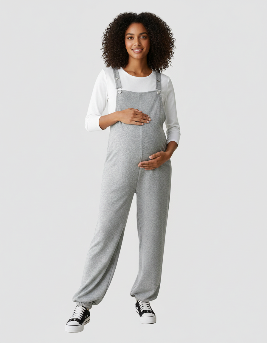 Pregnant woman in grey wide-leg maternity overalls with suspended straps over a white long-sleeve top.
