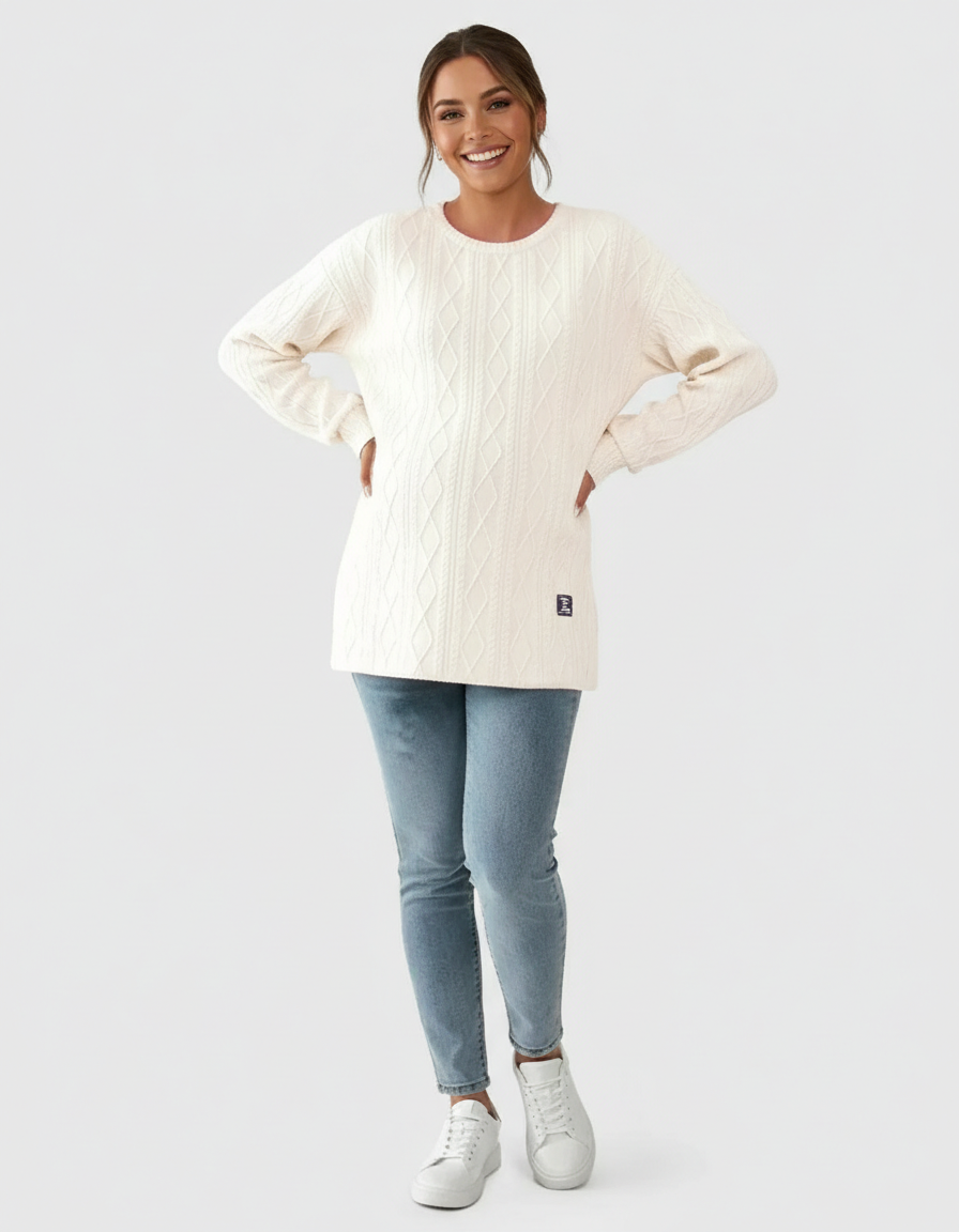 Smiling pregnant woman in a cream textured loose-fit maternity top and light blue jeans.