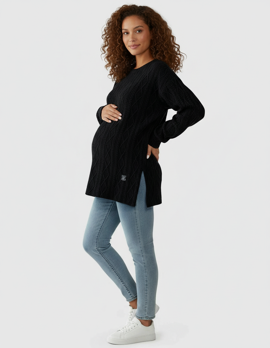 Pregnant woman in a black textured loose-fit maternity top with side slits and light wash jeans.