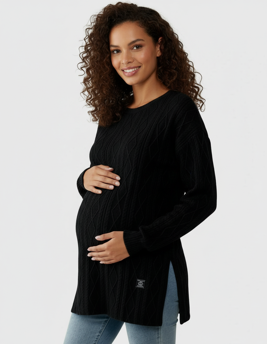 Smiling pregnant woman in a black textured loose-fit maternity top with side slits and light blue jeans.