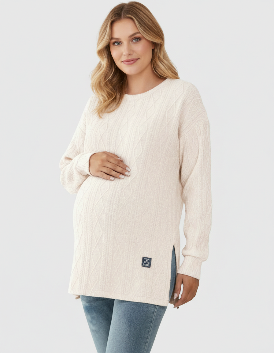 Blonde pregnant woman in a cream textured loose-fit maternity top with side slits and a small logo.