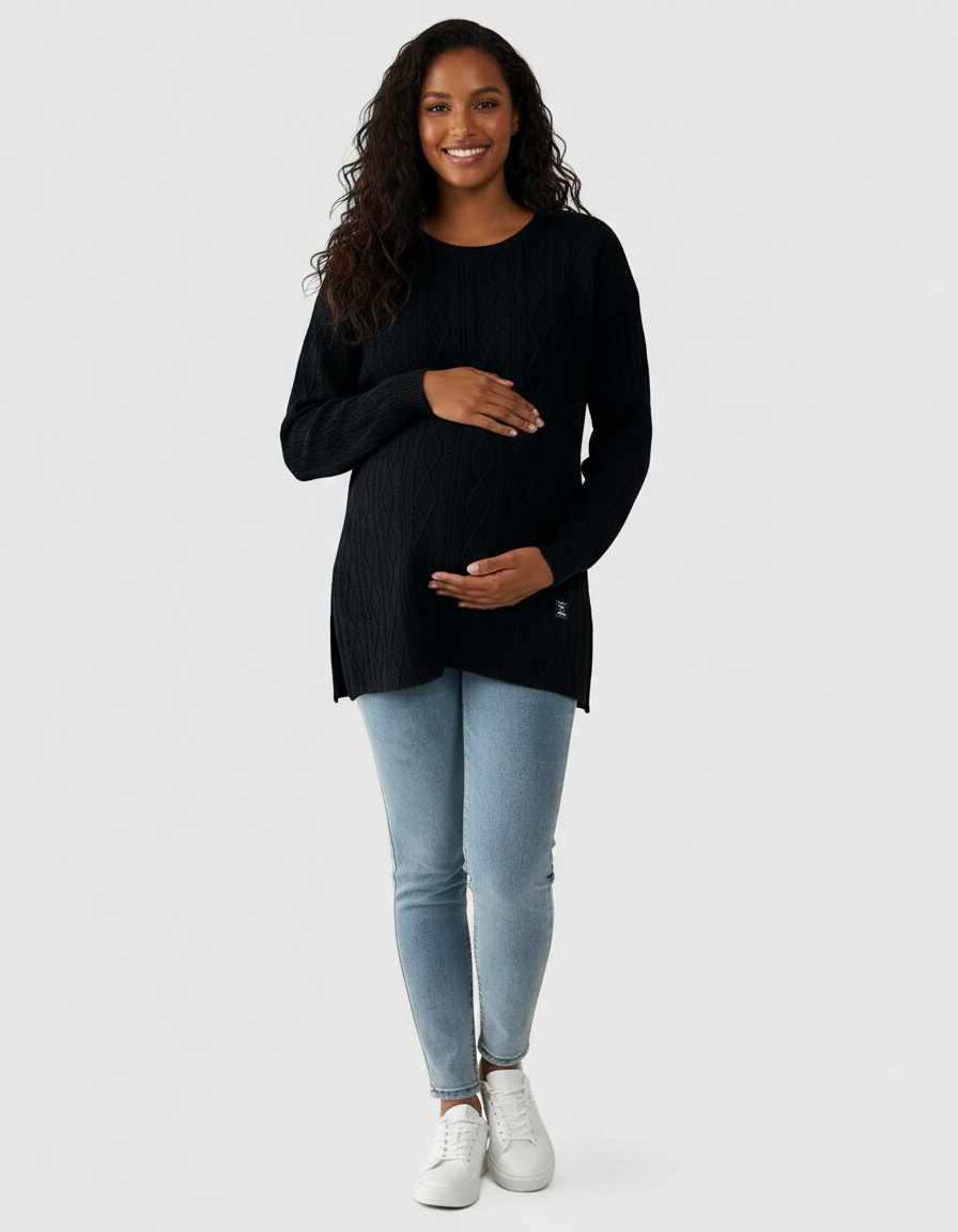 Smiling pregnant woman in a black textured loose-fit maternity top with side slits and light wash jeans.