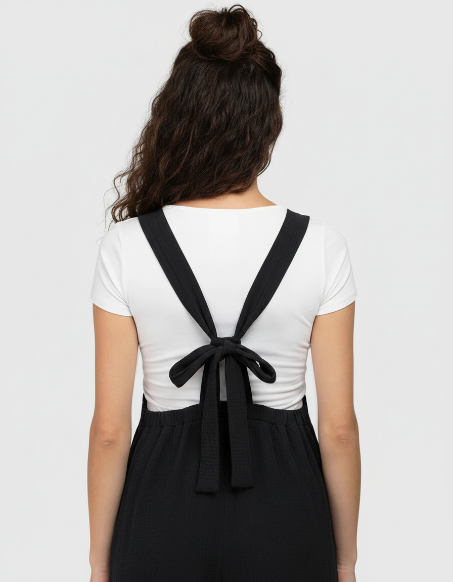 Woman from behind wearing a black tie-back wide-leg maternity jumpsuit over a white t-shirt.