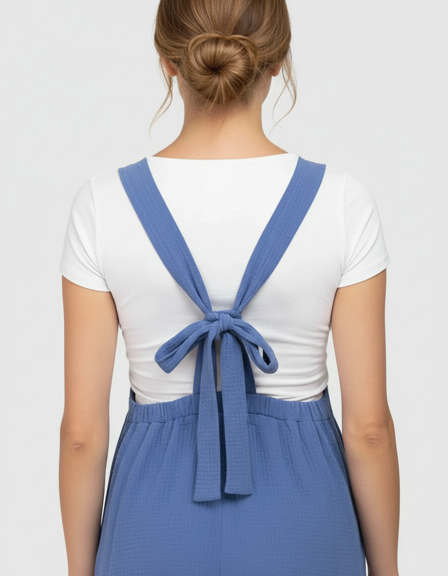 Woman in blue tie-back wide-leg maternity jumpsuit with a white top, showing the back detail.