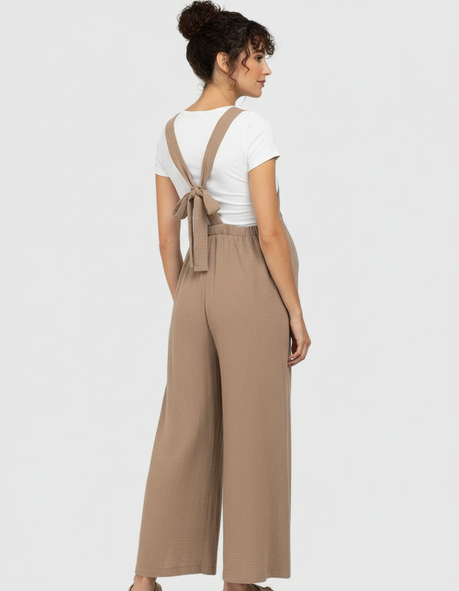 Maternity jumpsuit: brown wide-leg, textured fabric, tie-back straps over a white tee.