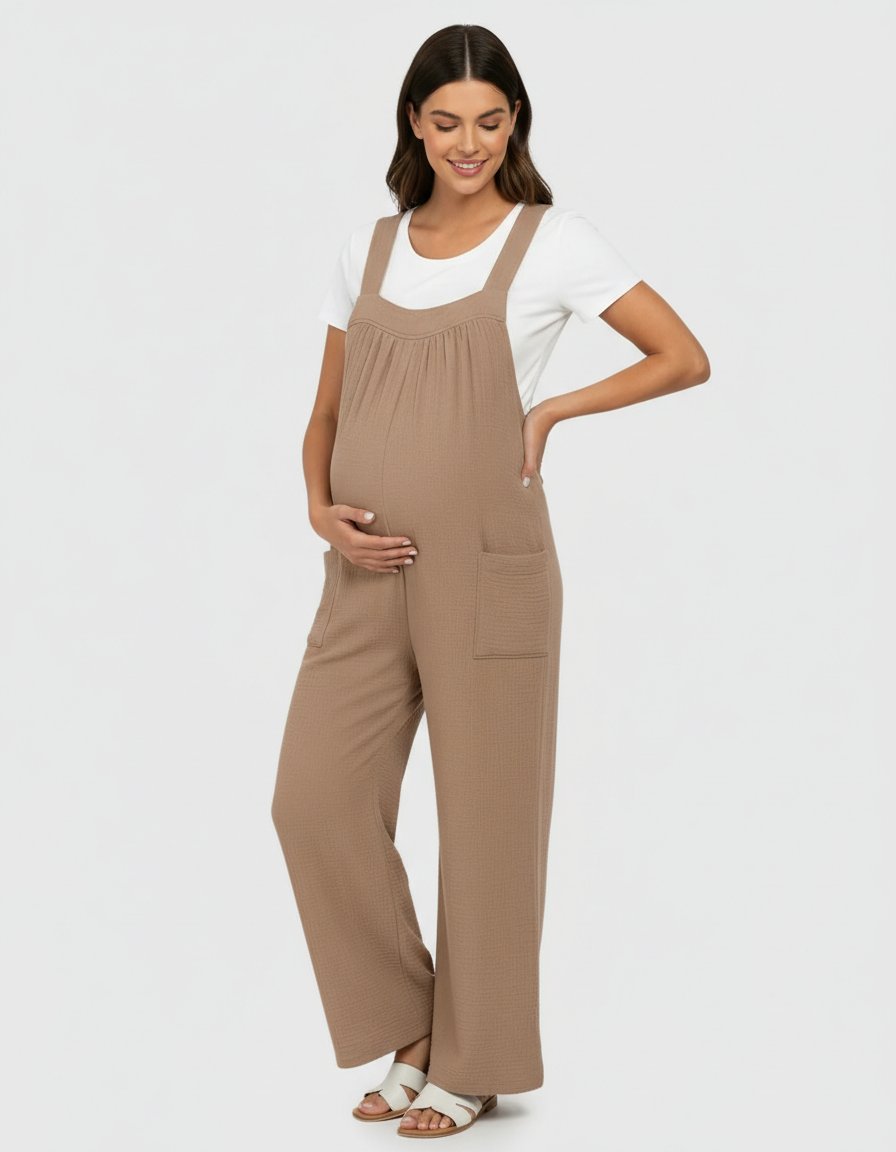 Pregnant woman in a brown textured wide-leg maternity jumpsuit with a white tee, smiling.