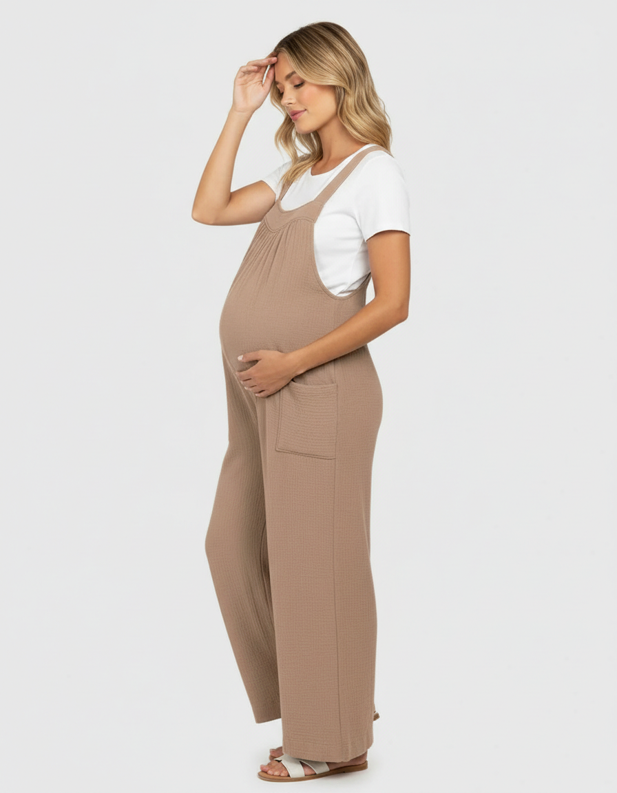 Pregnant woman in a beige ribbed wide-leg maternity jumpsuit with pockets and a white tee.
