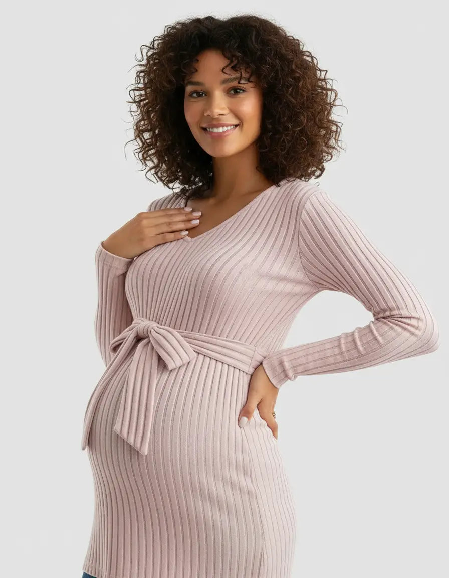 Smiling pregnant woman in a pink ribbed tie-waist maternity top with long sleeves and a V-neck.