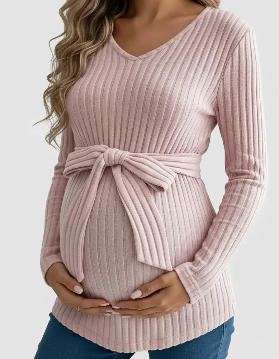 Pregnant woman wearing a pink ribbed tie-waist maternity top with long sleeves and a V-neck.