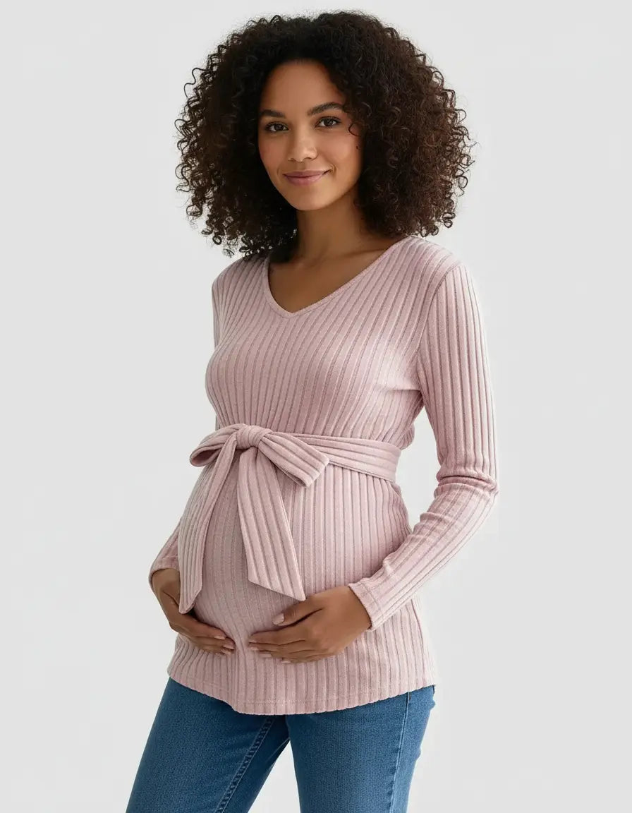 Smiling pregnant woman in a pink ribbed tie-waist maternity top and jeans.