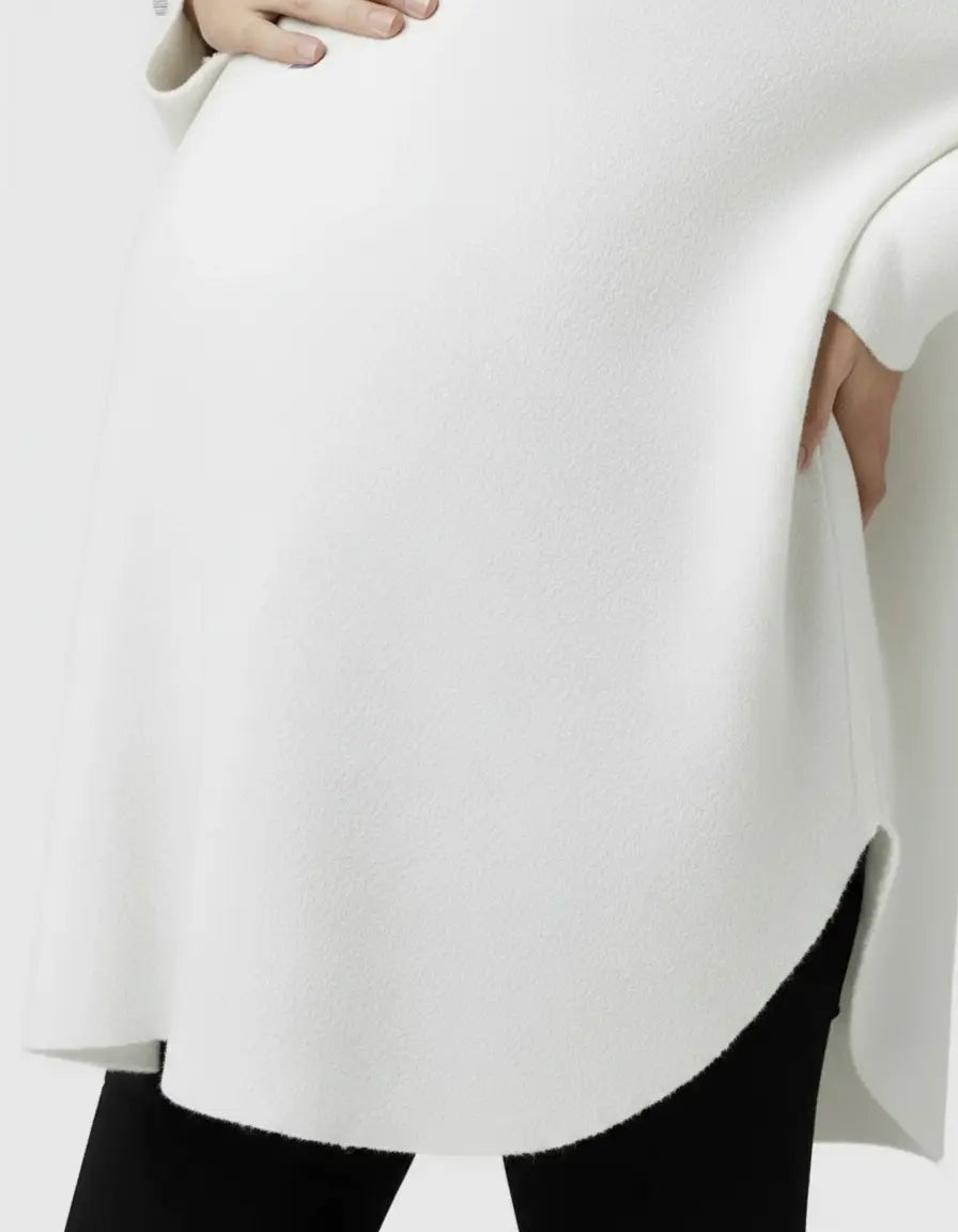 White wool blend relaxed maternity sweater with a rounded hem and side slit, worn by a pregnant model.