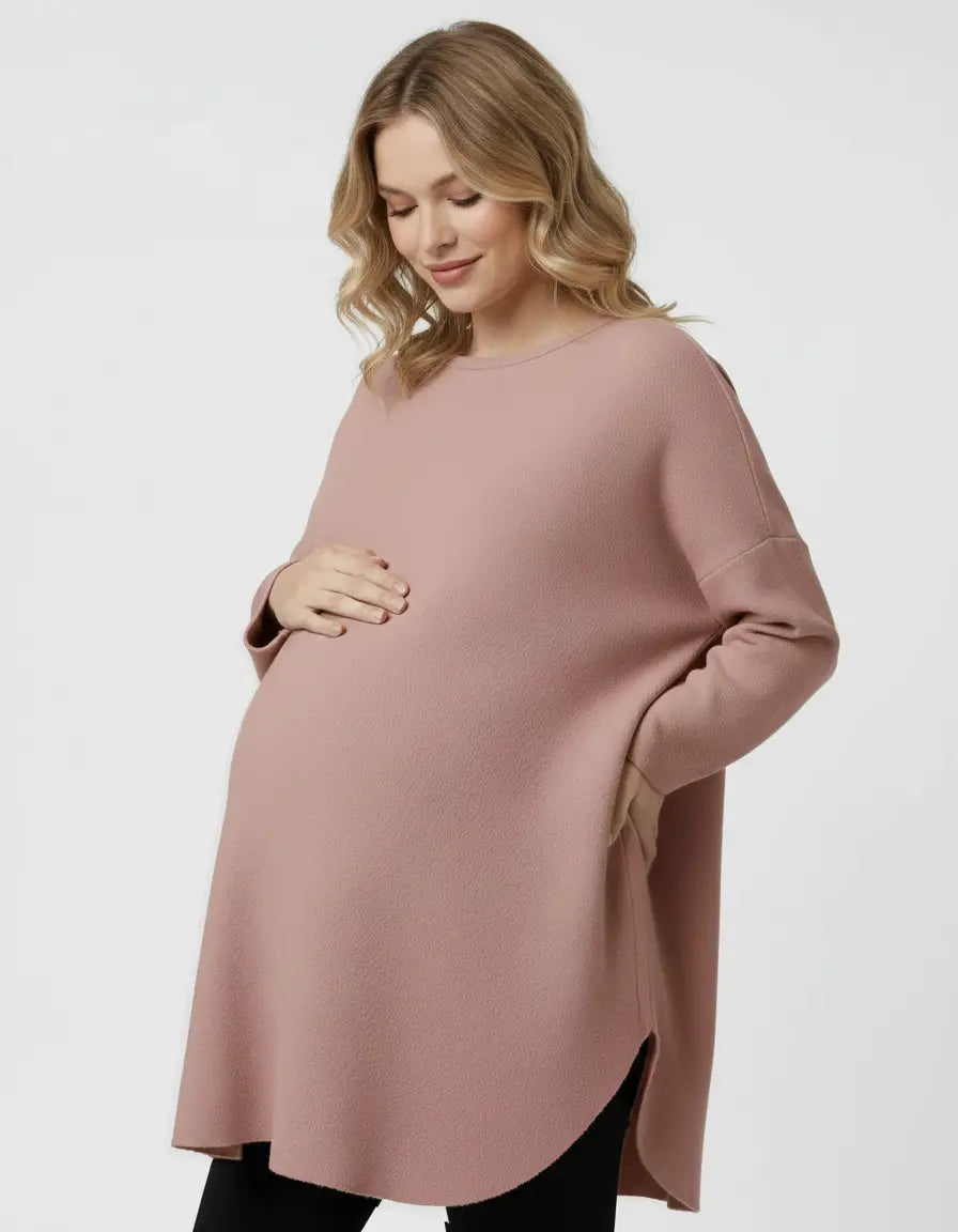 Blonde pregnant woman wearing a relaxed fit, dusty rose wool blend maternity sweater with a rounded hem.