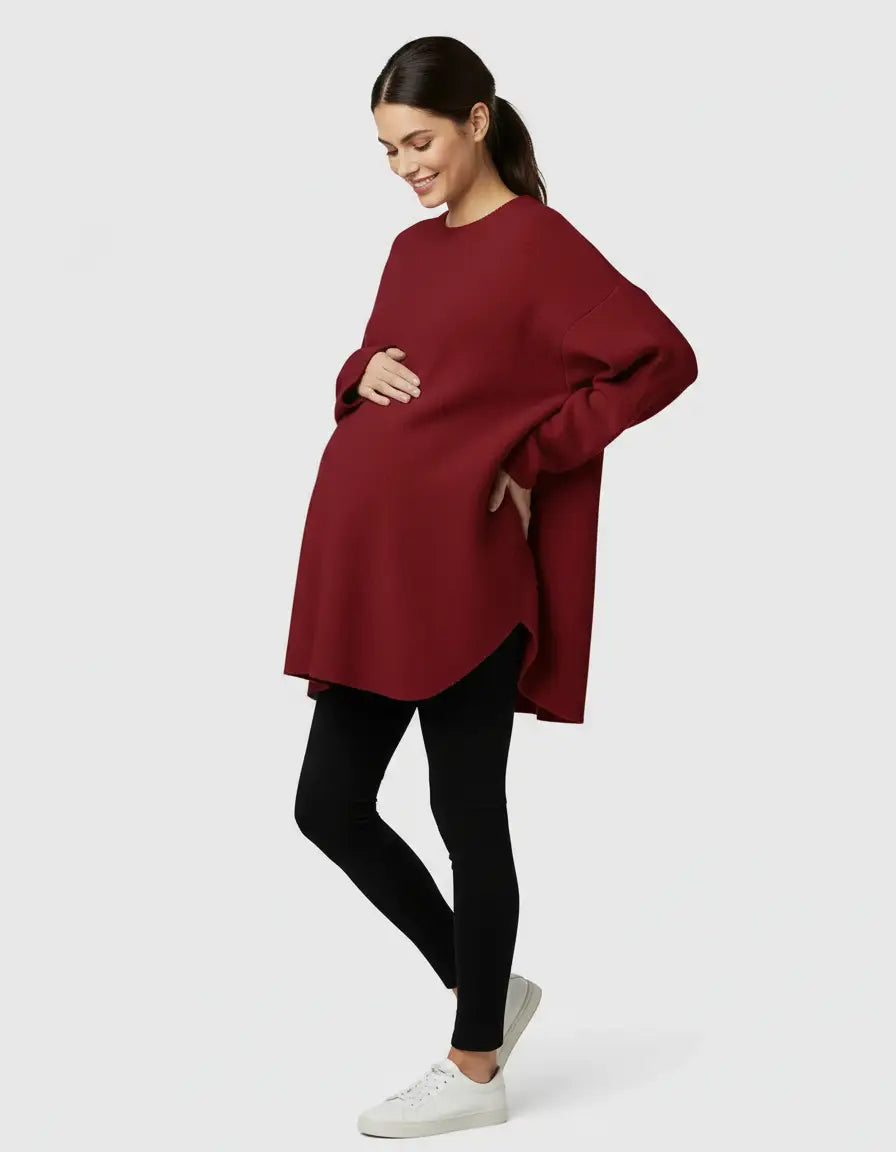 Smiling pregnant woman in a relaxed fit, warm wool blend red maternity sweater and black leggings.