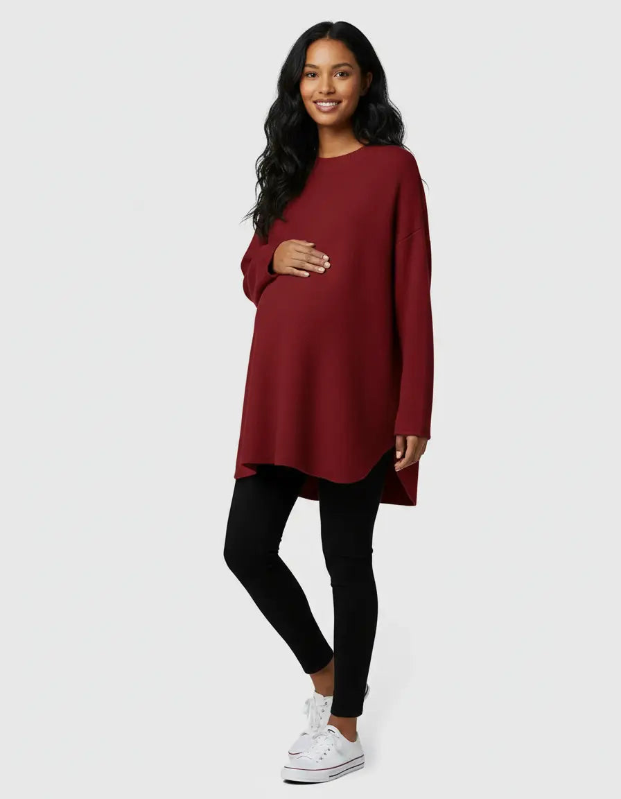 Smiling pregnant woman in a relaxed fit, long-sleeve, dark red wool blend maternity sweater and black leggings.