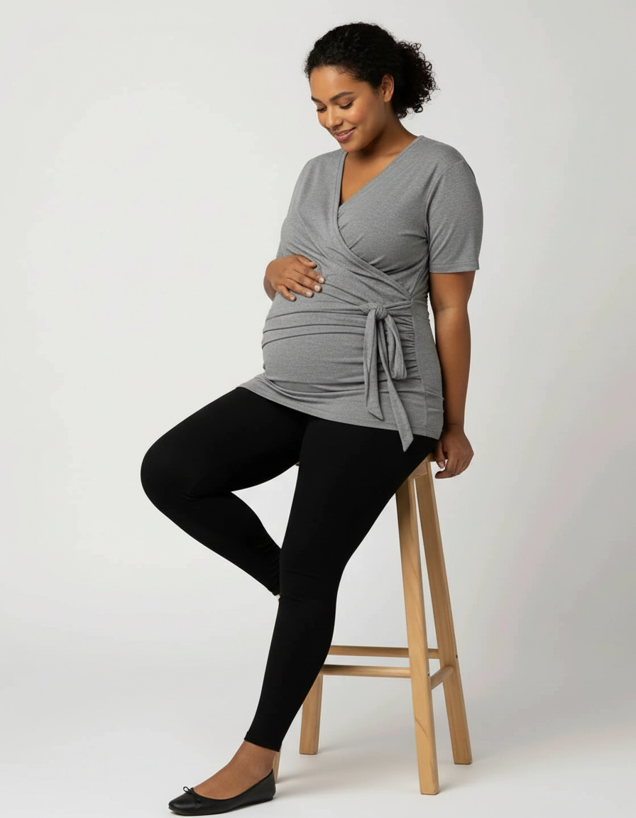 Pregnant woman in a gray 3-in-1 skin-to-skin nursing wrap top and black leggings, smiling.