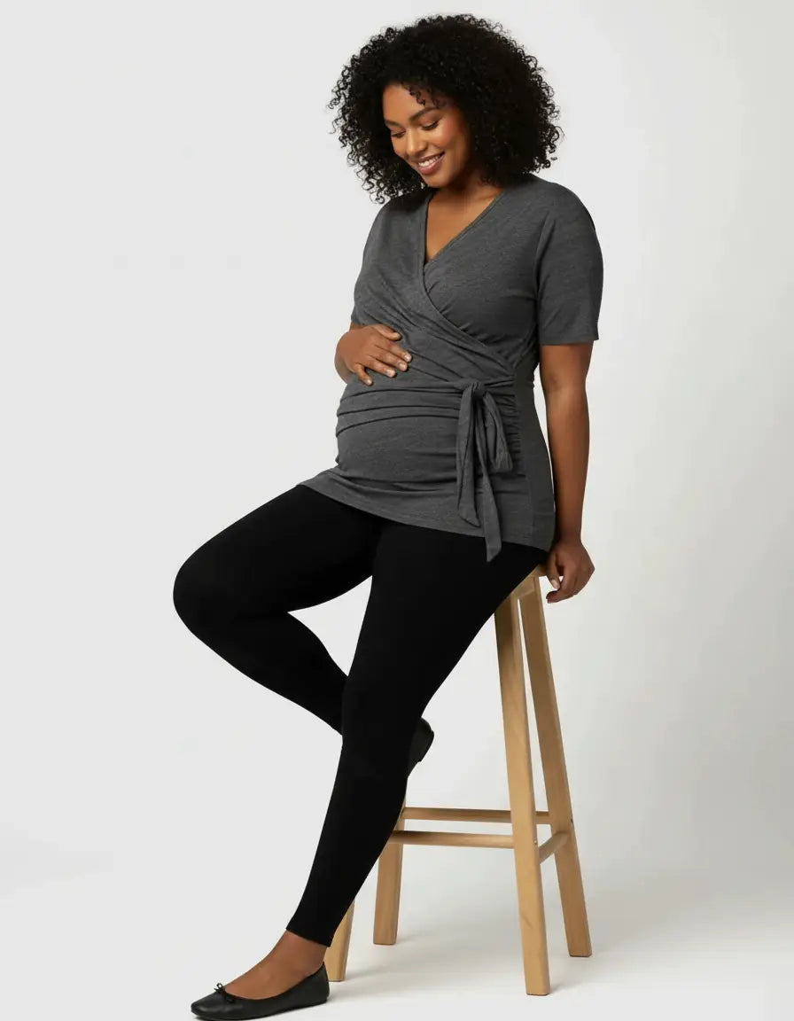 Smiling pregnant woman in a gray 3-in-1 skin-to-skin nursing wrap top and black leggings.