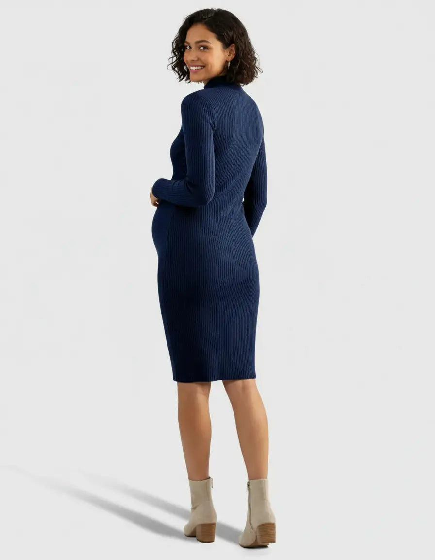 Smiling pregnant woman in a navy ribbed knit wrap nursing midi dress and beige boots.