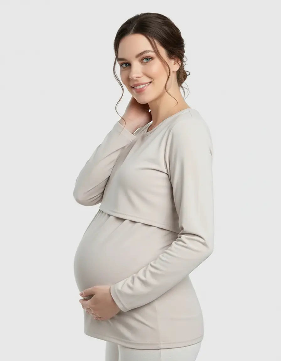 Smiling pregnant woman wearing a beige long-sleeve round neck nursing top with feeding port.