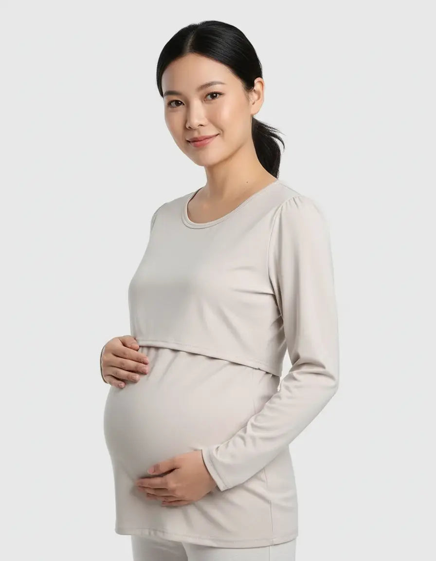 Smiling pregnant woman in a light beige, long-sleeved round neck nursing top with feeding port.