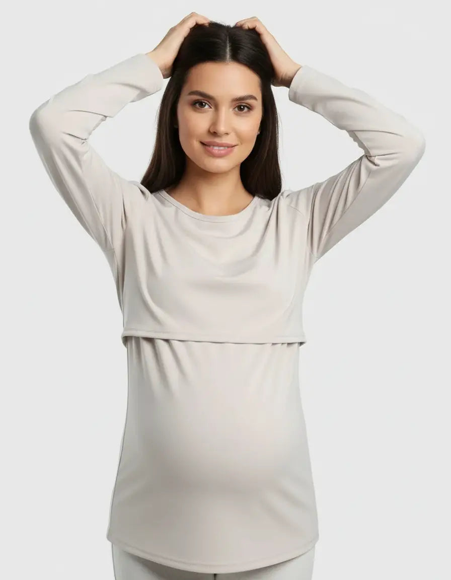 Smiling pregnant woman in a light beige long-sleeve round neck nursing top with feeding port.
