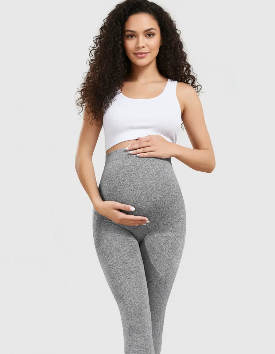 Pregnant woman in gray belly-support sculpting maternity activewear leggings and a white crop top.