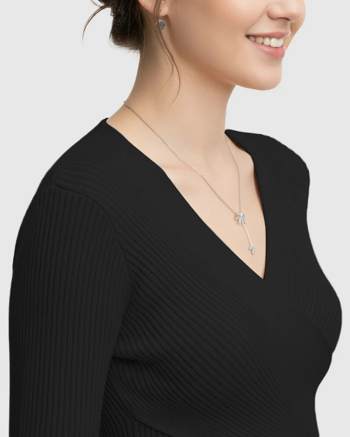Woman wearing a black faux-wrap ribbed maternity top with a V-neck and long sleeves.