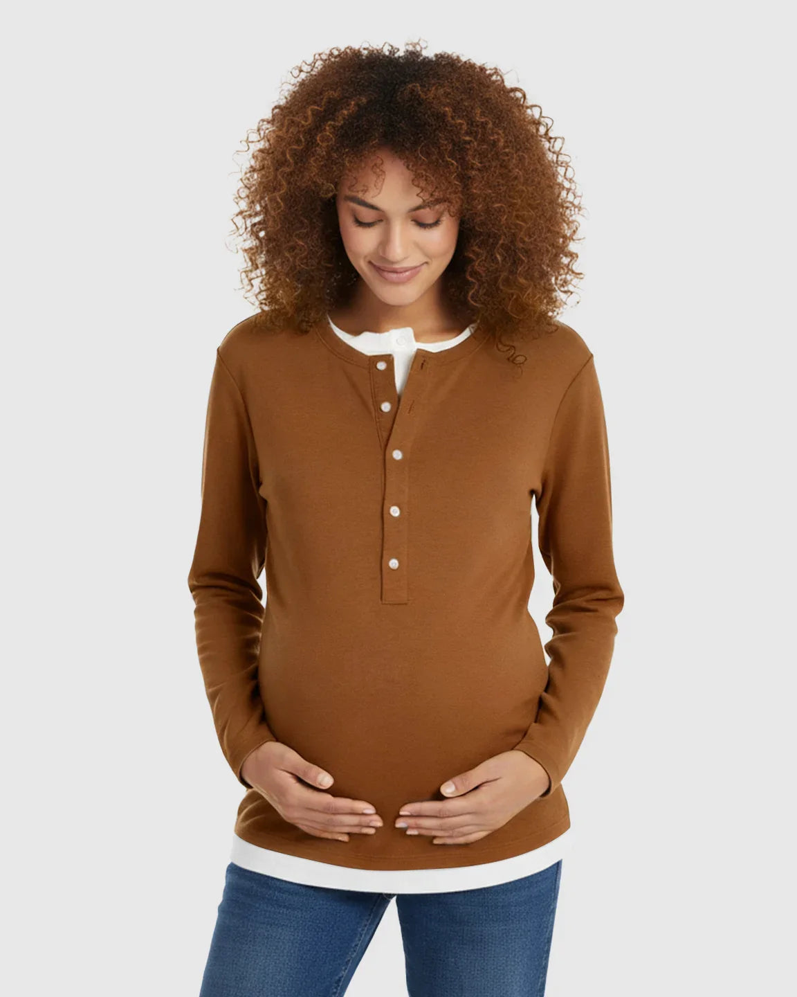 Pregnant woman in a brown long-sleeve henley maternity and nursing top with a white undershirt.