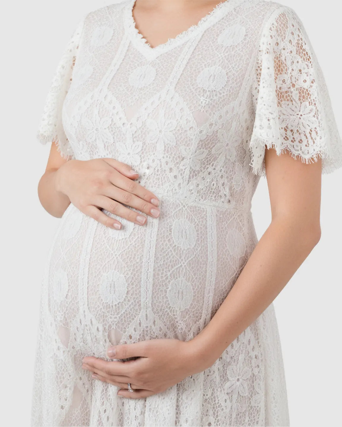 White vintage lace maternity gown with flutter sleeves and V-neck, highlighting a pregnant belly.