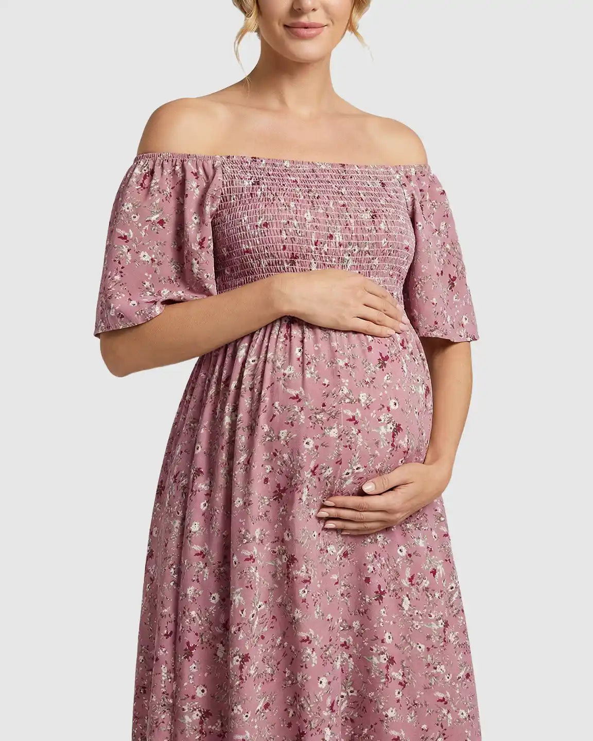 Maternity midi dress in pink floral print with off-shoulder smocked top, flutter sleeves, and tiered skirt.