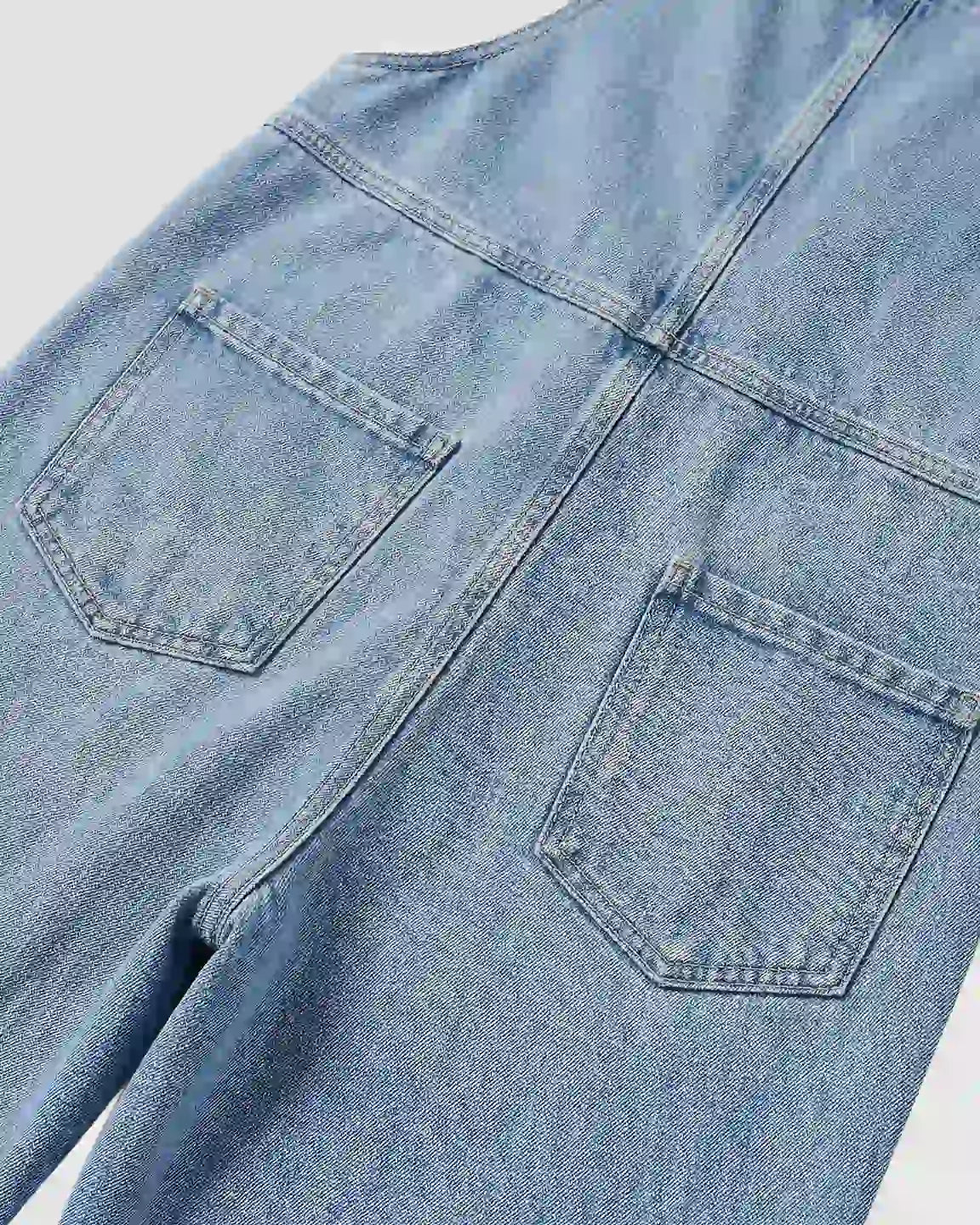 Light wash blue denim maternity jumpsuit with two back pockets and visible stitching.
