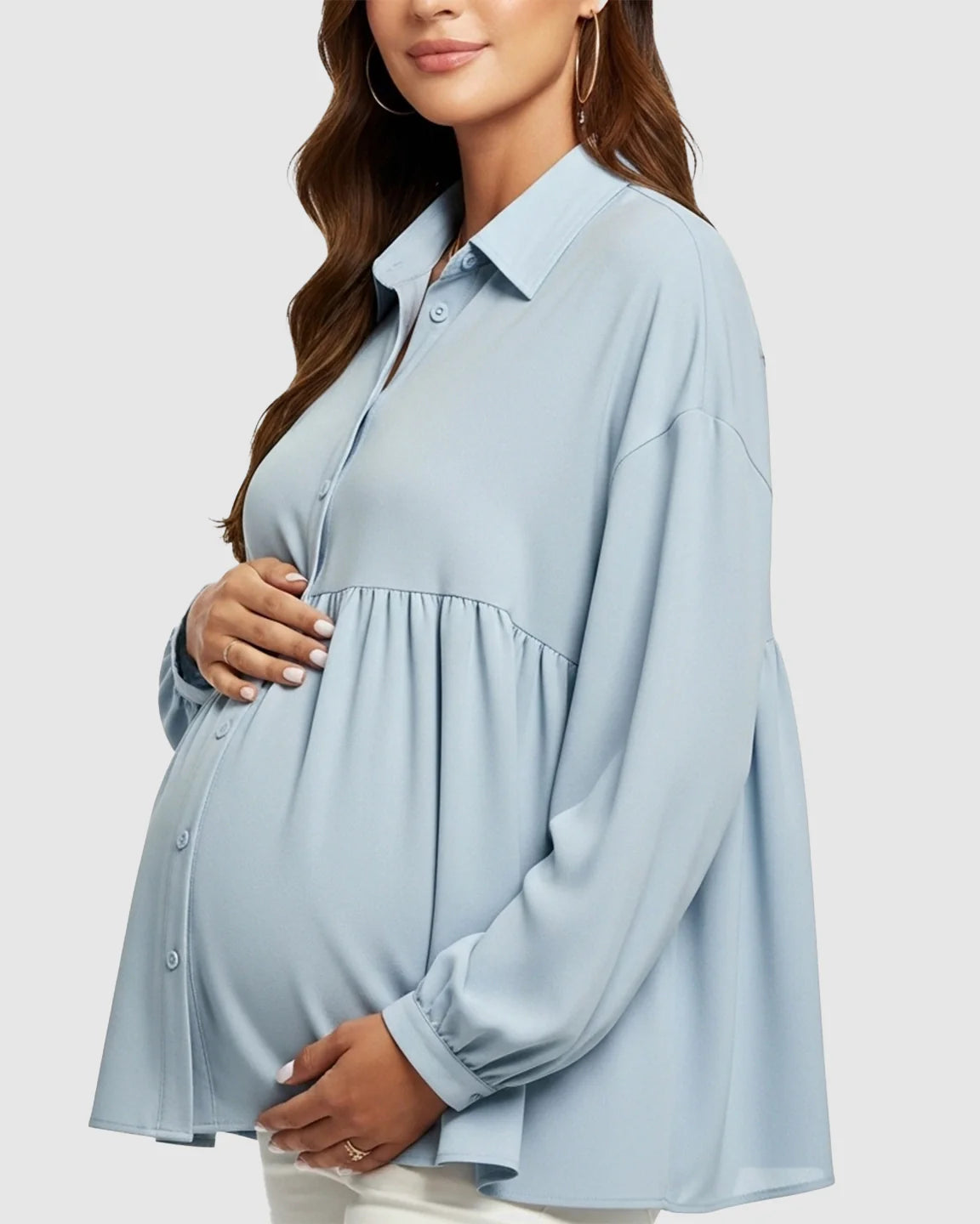 Maternity model in a light blue chiffon babydoll shirt with lapel collar and button-down front, cradling her bump.