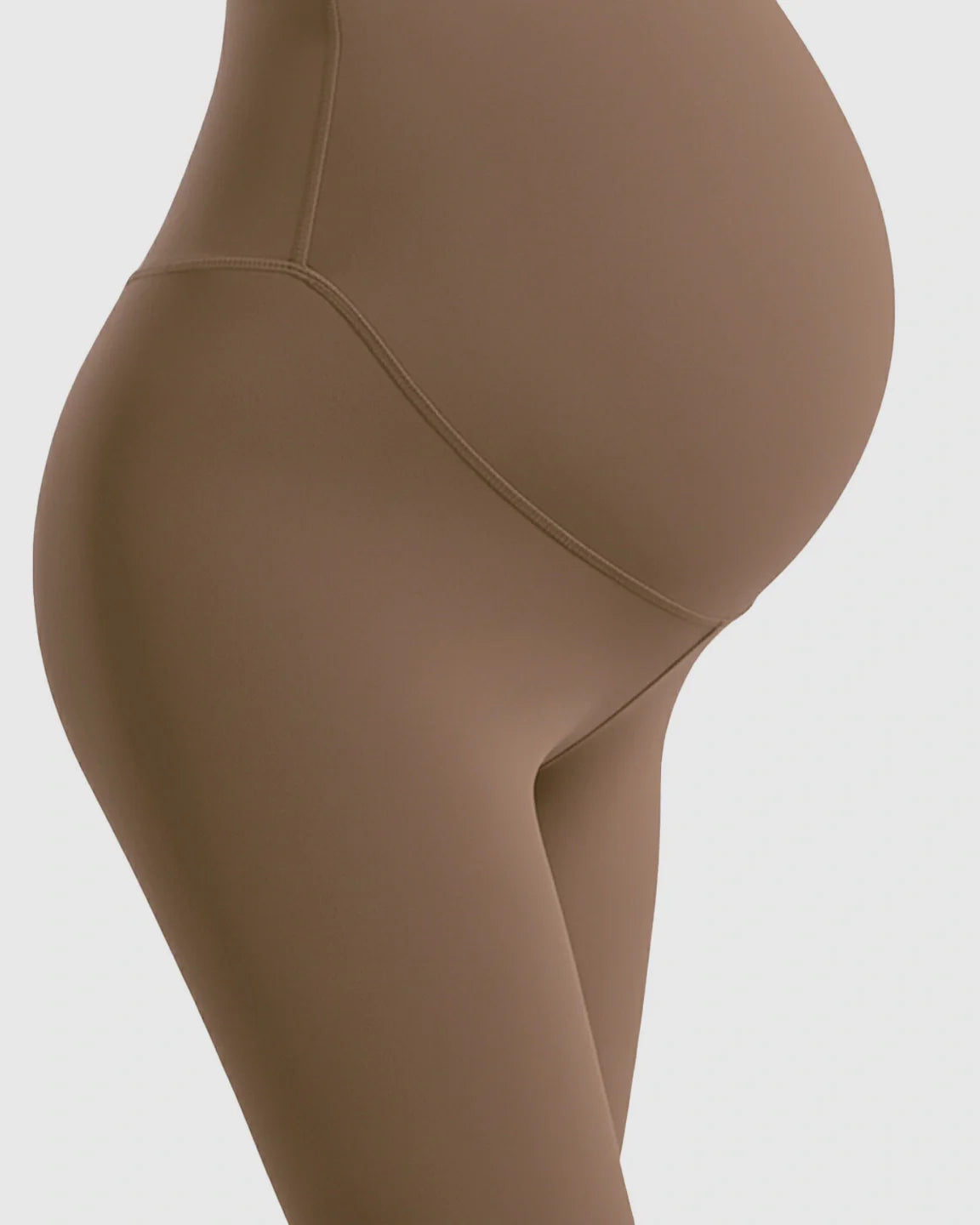 Close-up of a pregnant belly wearing brown double-layer maternity leggings with support panel.