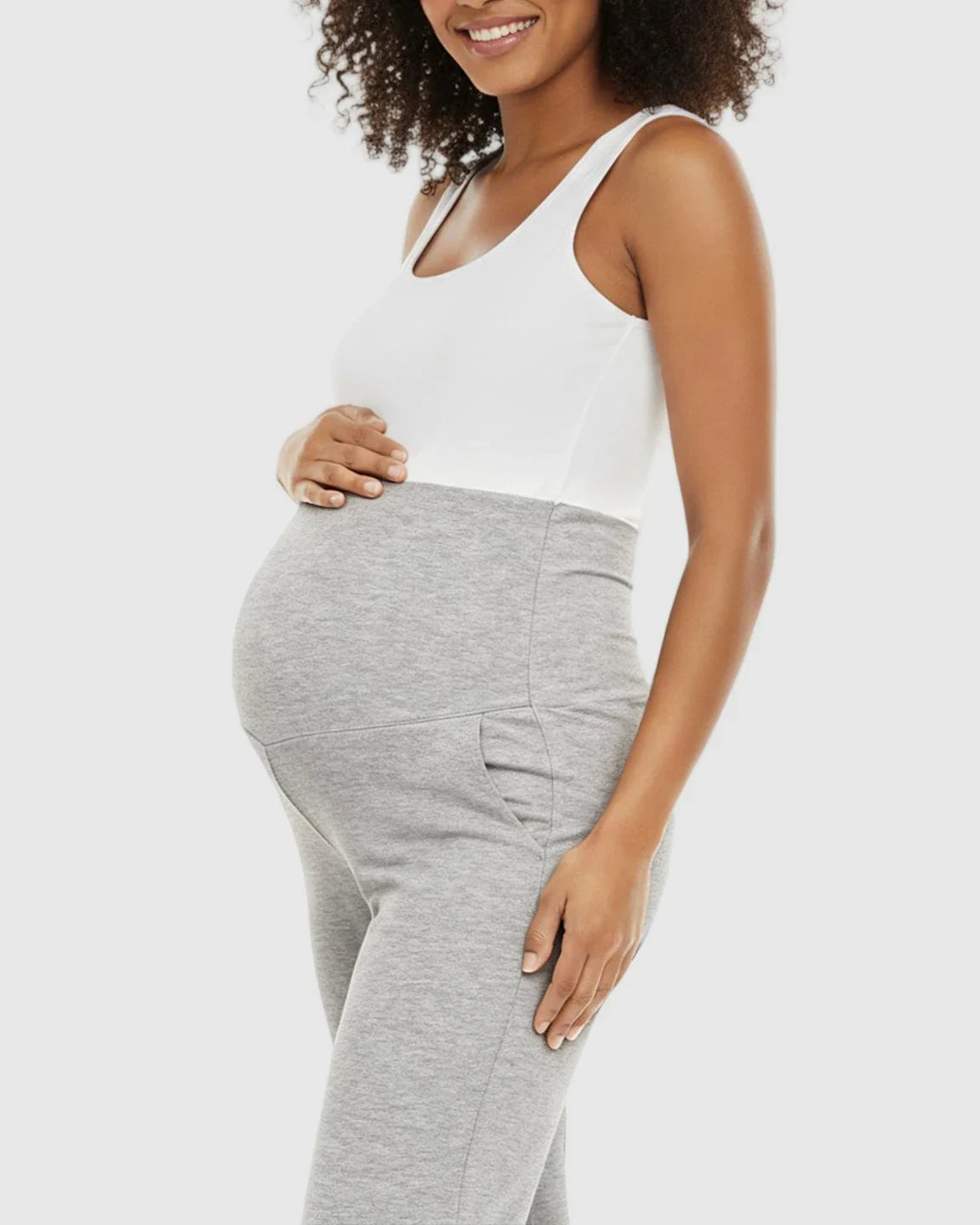 Pregnant woman in a white tank top and gray foldable waistband wide-leg maternity lounge pants.