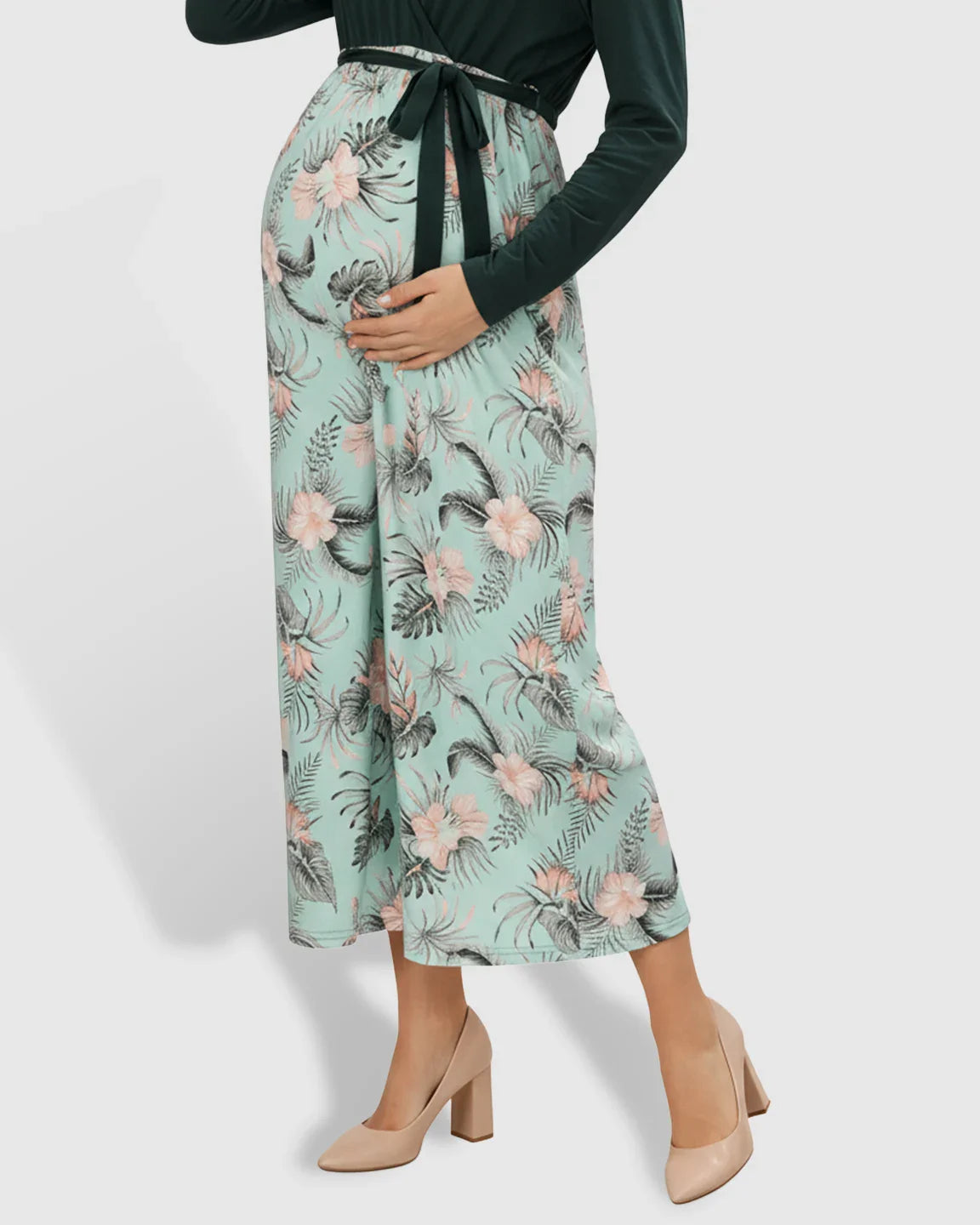 Maternity midi dress: deep green long-sleeve V-neck top, floral mint skirt, tie waist, nude heels.