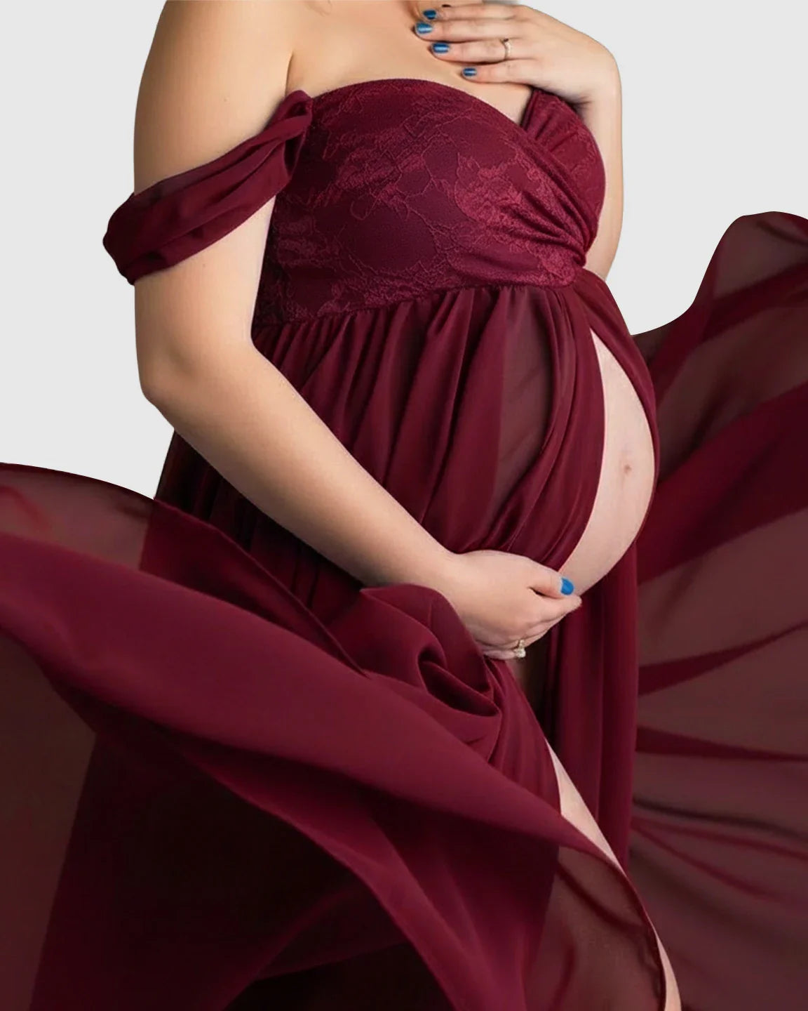 Pregnant woman in a flowing, off-shoulder burgundy chiffon maternity gown with a lace bodice and open front.