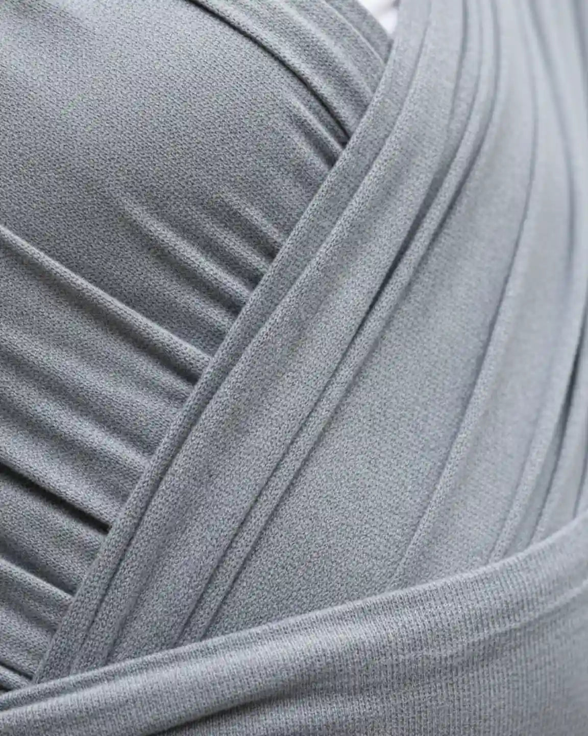 Close-up of a soft, breathable gray adjustable wrap-around baby carrier with subtle texture.