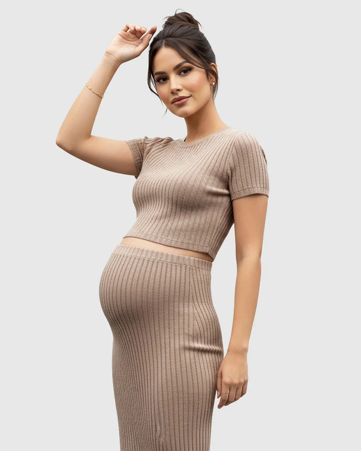 Pregnant woman in a beige ribbed crop top and side-slit bodycon maternity skirt set.