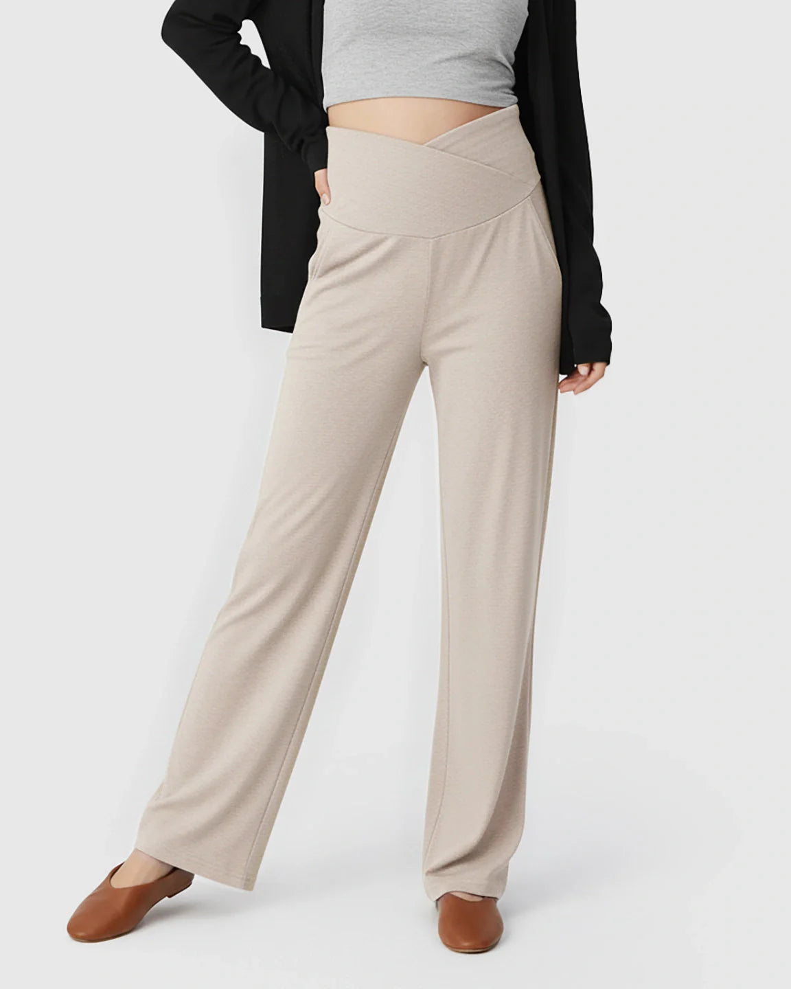 Beige crossover waist wide-leg maternity lounge pants with deep side pockets, worn by a pregnant woman.