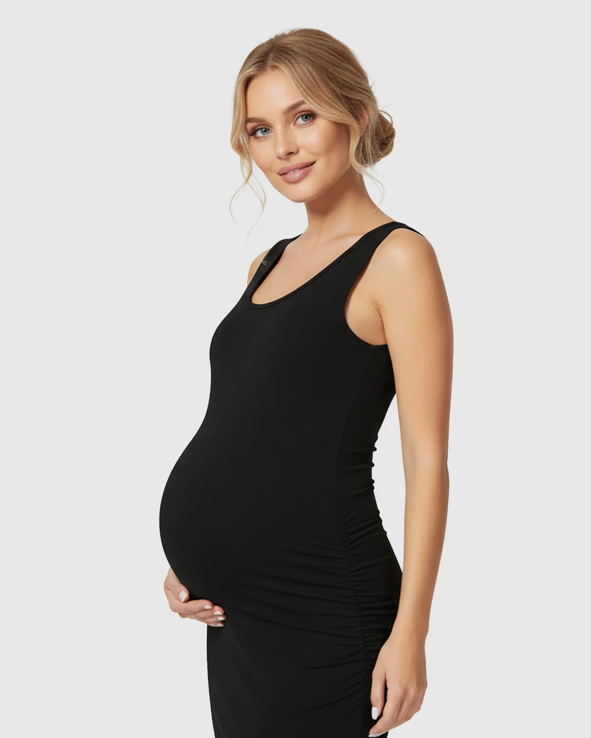 Pregnant woman in a black sleeveless bodycon maternity dress with side ruching, smiling.