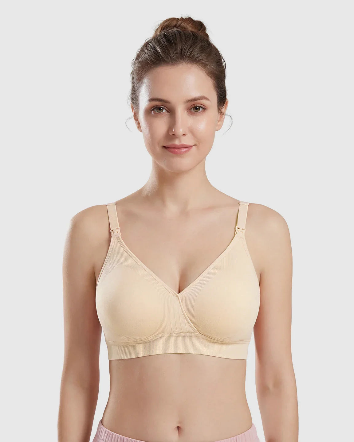 Woman wearing a seamless beige cross-front wireless nursing bra with ribbed details.