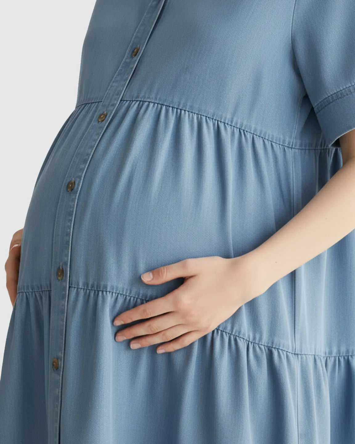 Pregnant woman in a blue tiered denim casual maternity midi dress with button-front.