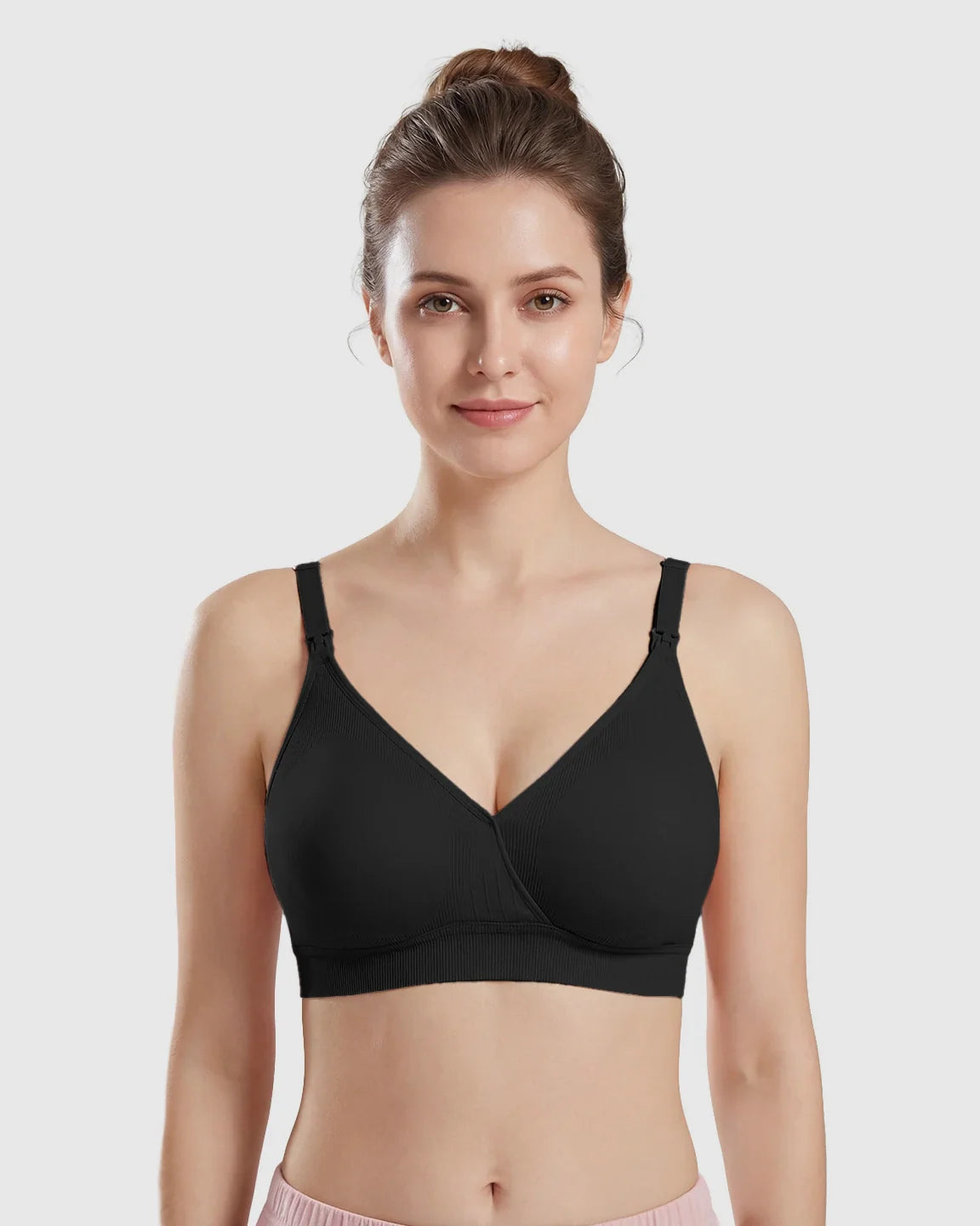 Woman wearing a black seamless cross-front wireless nursing bra with ribbed band.