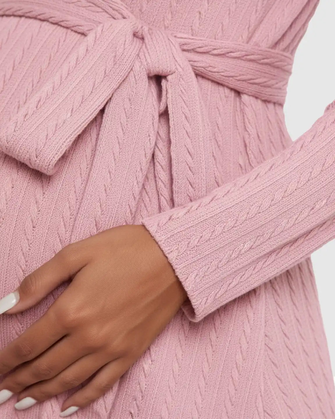Close-up of a pink ribbed tie-waist maternity midi dress, showing the cable knit texture and tied waist.